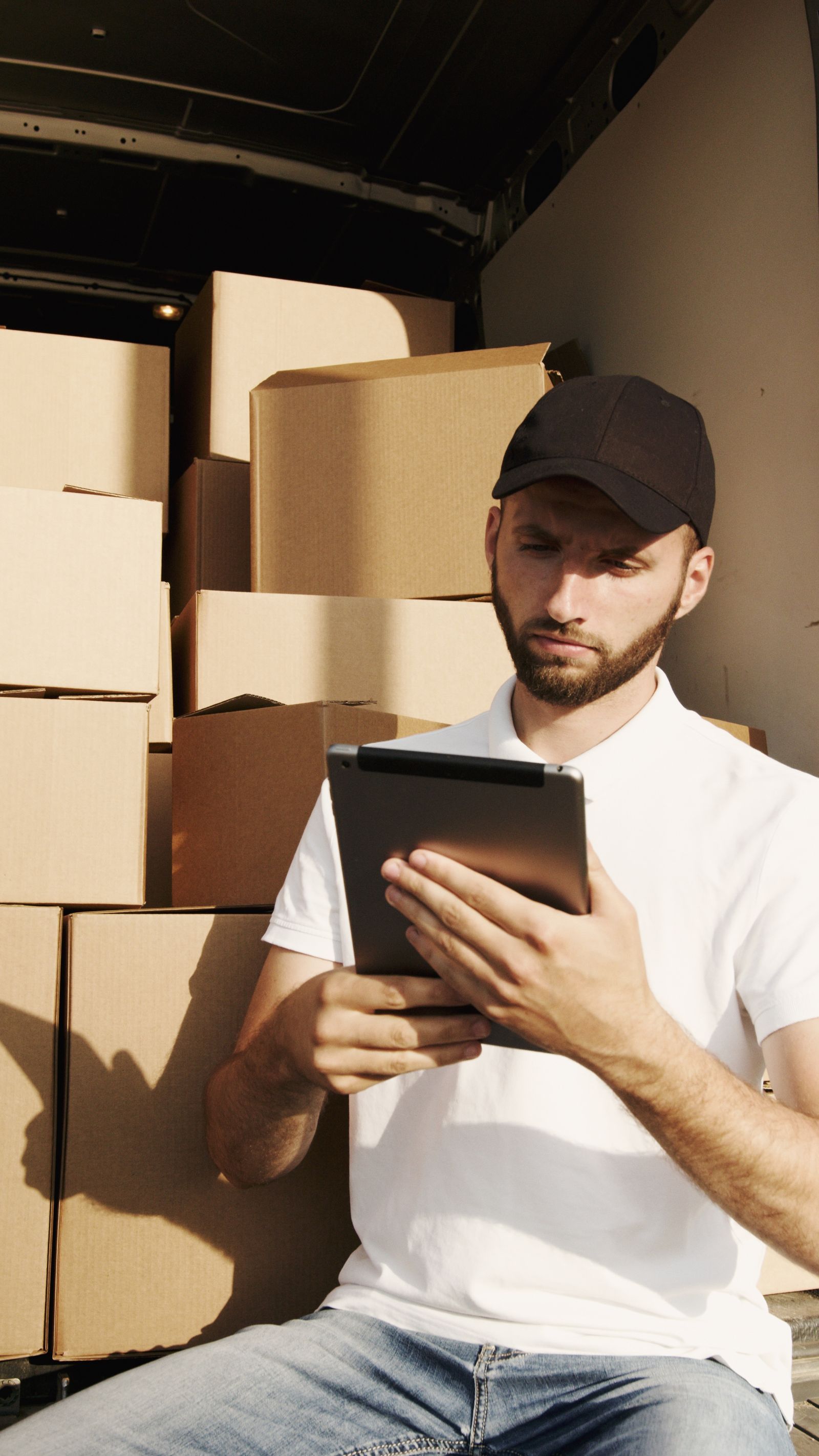 Livreur vérifiant une commande sur tablette au milieu des colis